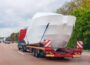 Truck semi-trailer carrier towing new wrapped yacht boat on highway road summer day. Delivering transportation new private Luxury ship. Rich recreation lifestyle. Service maintenance transportation.