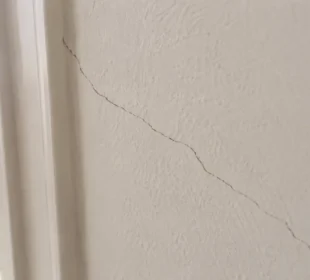 Hairline crack running through painted plaster wall in an Australian home